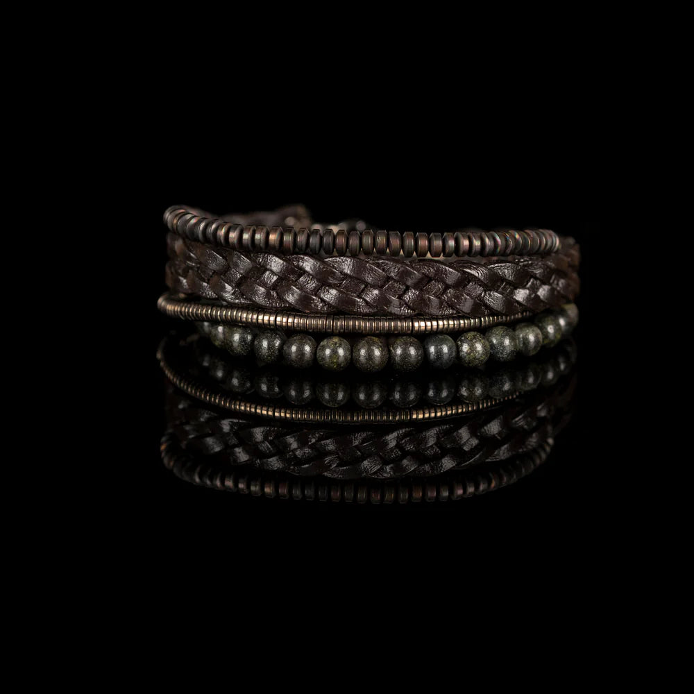 Men's handcrafted layered bracelet set featuring a dark brown braided genuine leather bracelet, natural green serpentine gemstone beads, bronze hematite heishi beads, and metallic spacer beads. Premium artisan men's bracelet stack photographed on a clean white background.
