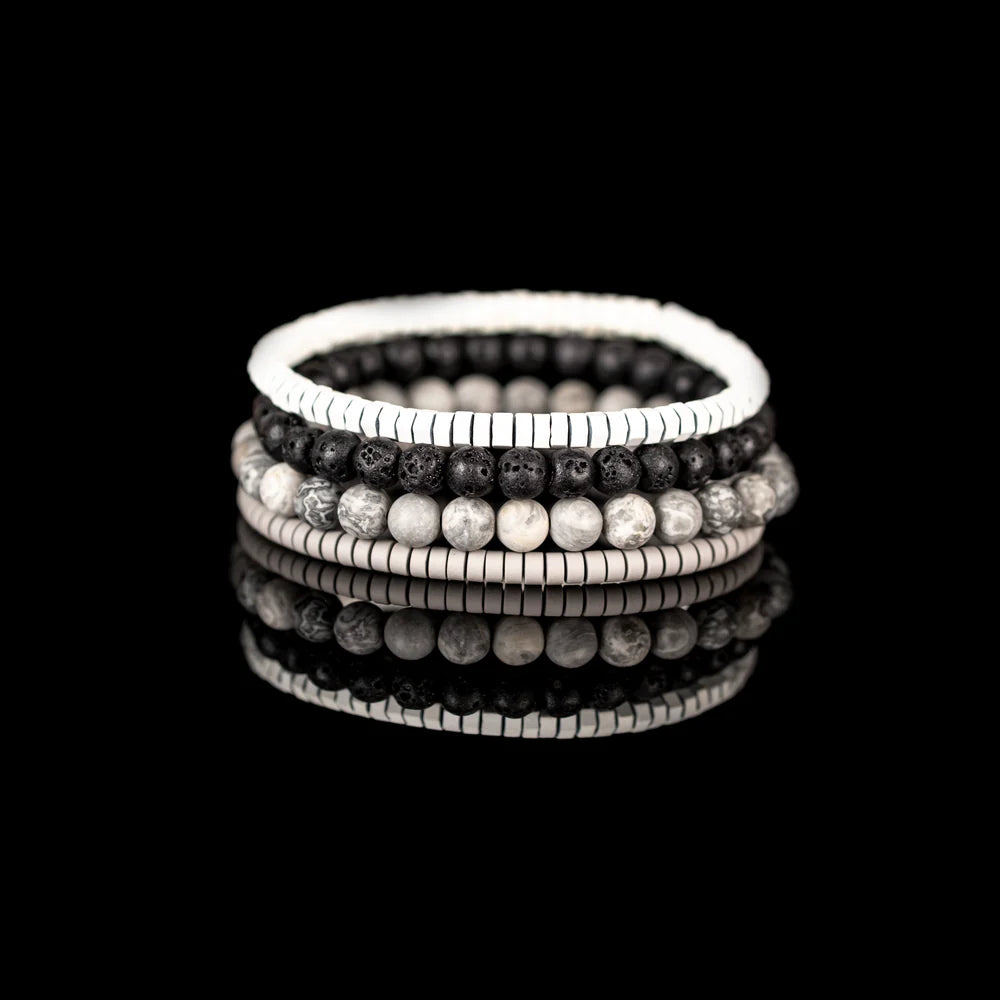 Men's handcrafted layered bracelet set featuring white heishi disc beads, black lava stone beads, natural white and gray jasper gemstone beads, and matte silver hematite heishi spacers. Premium minimalist men's bracelet stack photographed on a clean white background.