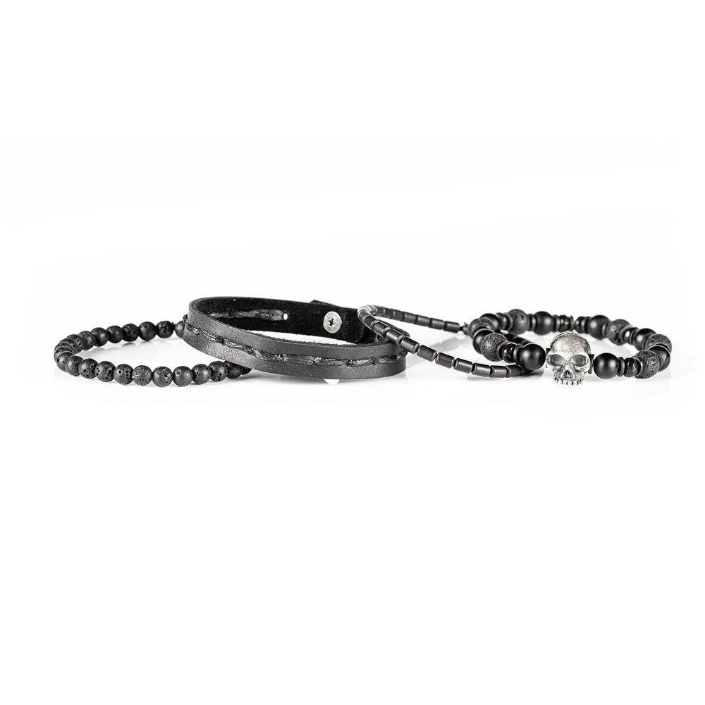 Men's handcrafted black leather wrap bracelet set featuring matte black onyx beads, natural lava stone beads, hematite accents, and a silver skull centerpiece. Premium layered men's bracelet stack photographed on a clean white background.