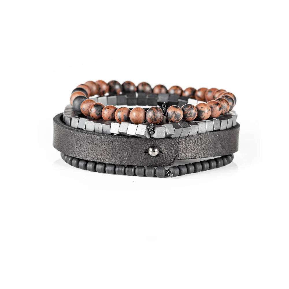 Men's handcrafted black leather wrap bracelet set featuring brown mahogany obsidian gemstone beads, matte black hematite cube beads, black seed beads, and a premium layered leather cuff with stitched detailing. Luxury men's bracelet stack photographed on a clean white background.
