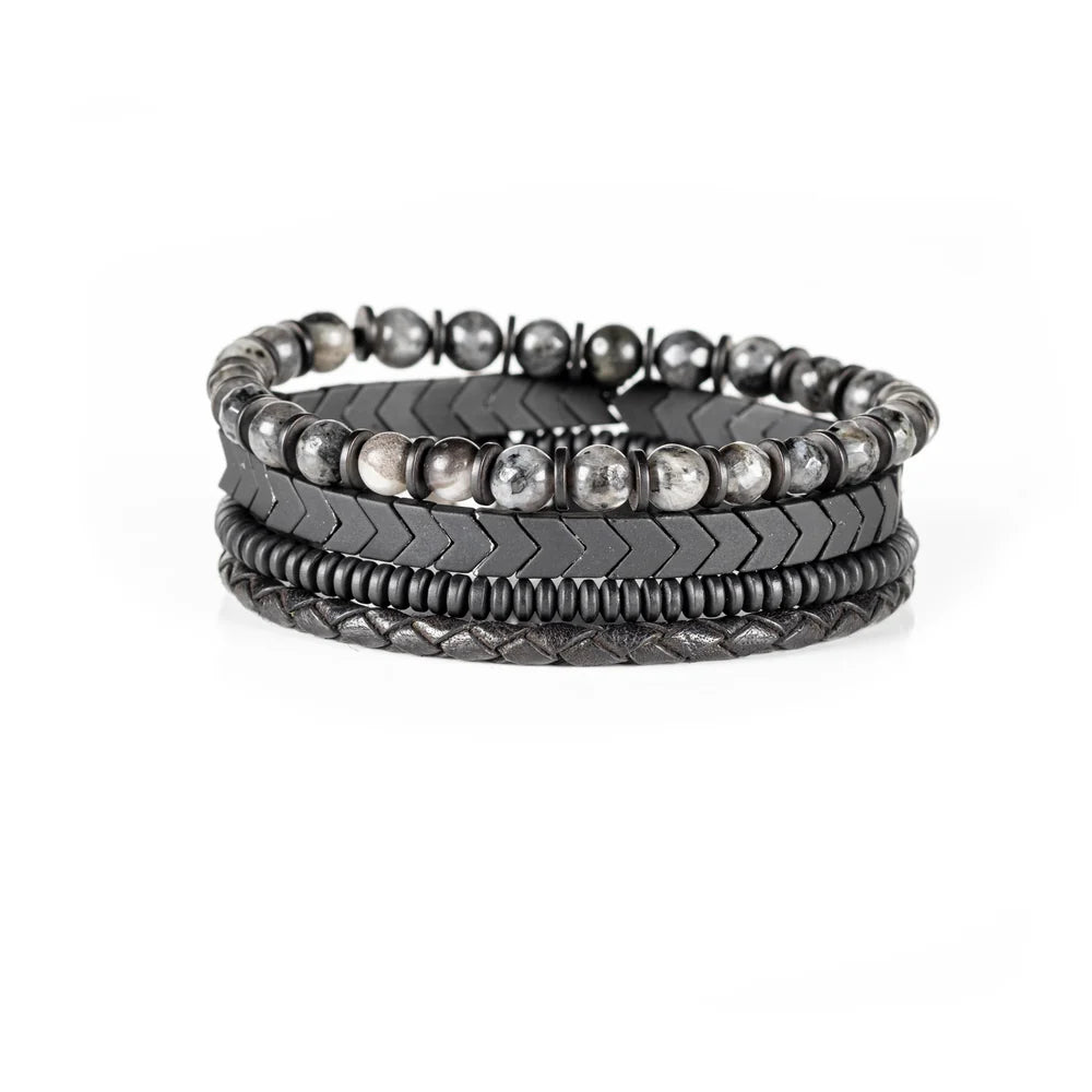 Men's handcrafted layered bracelet set featuring black leather wrap bands, braided leather, matte black hematite arrow beads, black spacer beads, and natural gray jasper gemstone beads. Premium men's stacked bracelet photographed on a clean white background.