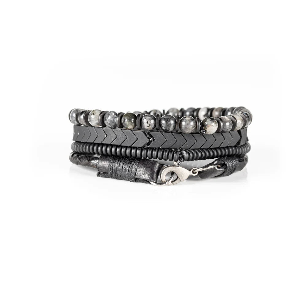Men's handcrafted layered bracelet set featuring black leather wrap bands, braided leather, matte black hematite arrow beads, black spacer beads, and natural gray jasper gemstone beads. Premium men's stacked bracelet photographed on a clean white background.
