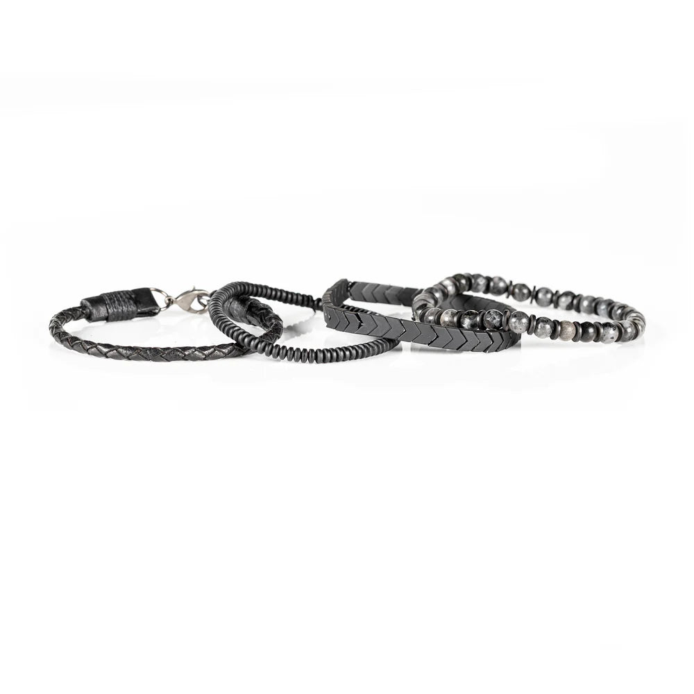 Men's handcrafted layered bracelet set featuring black leather wrap bands, braided leather, matte black hematite arrow beads, black spacer beads, and natural gray jasper gemstone beads. Premium men's stacked bracelet photographed on a clean white background.