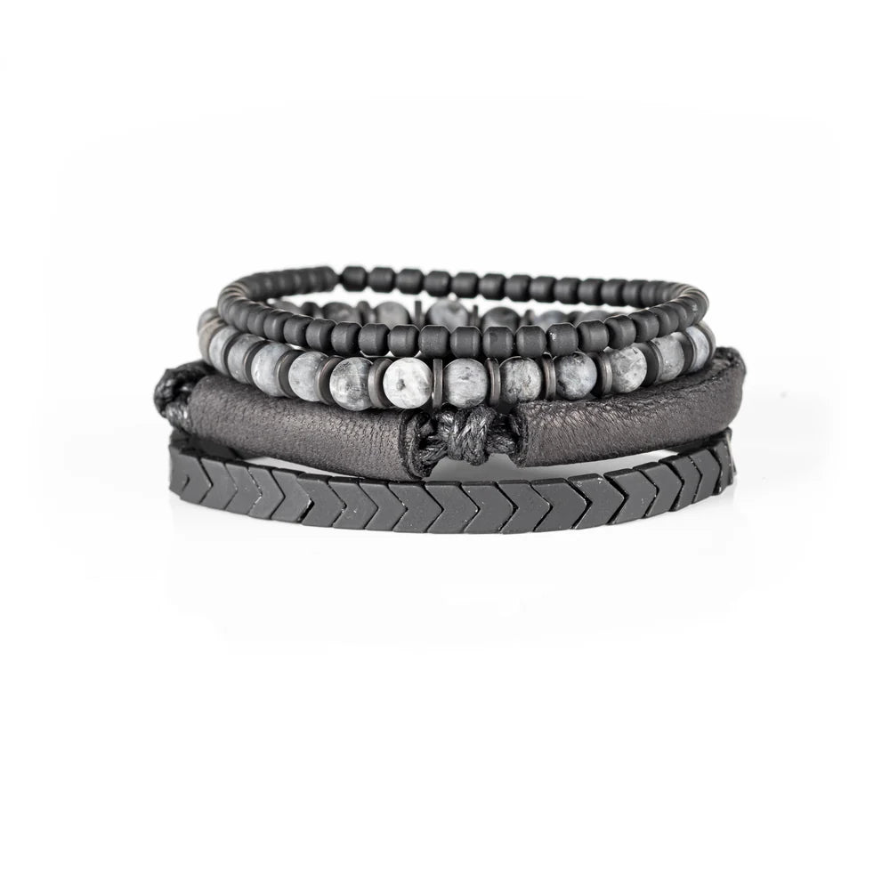 Men's handcrafted layered bracelet set featuring black leather wrap bands, matte black hematite arrow beads, black seed beads, and natural gray jasper gemstone beads. Premium stacked men's bracelet with minimalist design photographed on a clean white background.