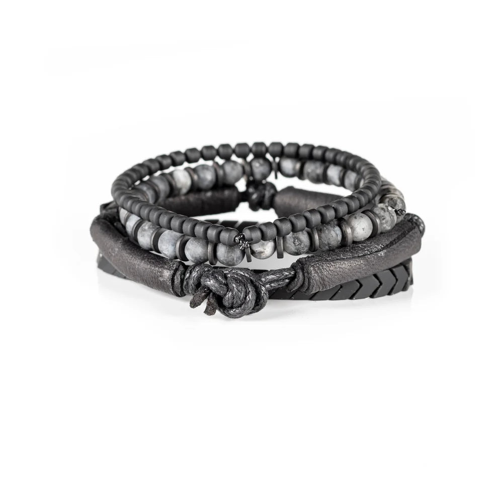 Men's handcrafted layered bracelet set featuring black leather wrap bands, matte black hematite arrow beads, black seed beads, and natural gray jasper gemstone beads. Premium stacked men's bracelet with minimalist design photographed on a clean white background.