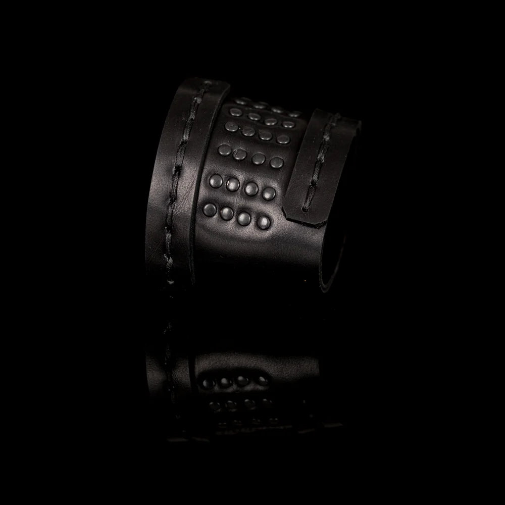 Black genuine leather cuff bracelet with hand-stitched wrap straps and black studded detailing, handcrafted statement accessory on a white background.