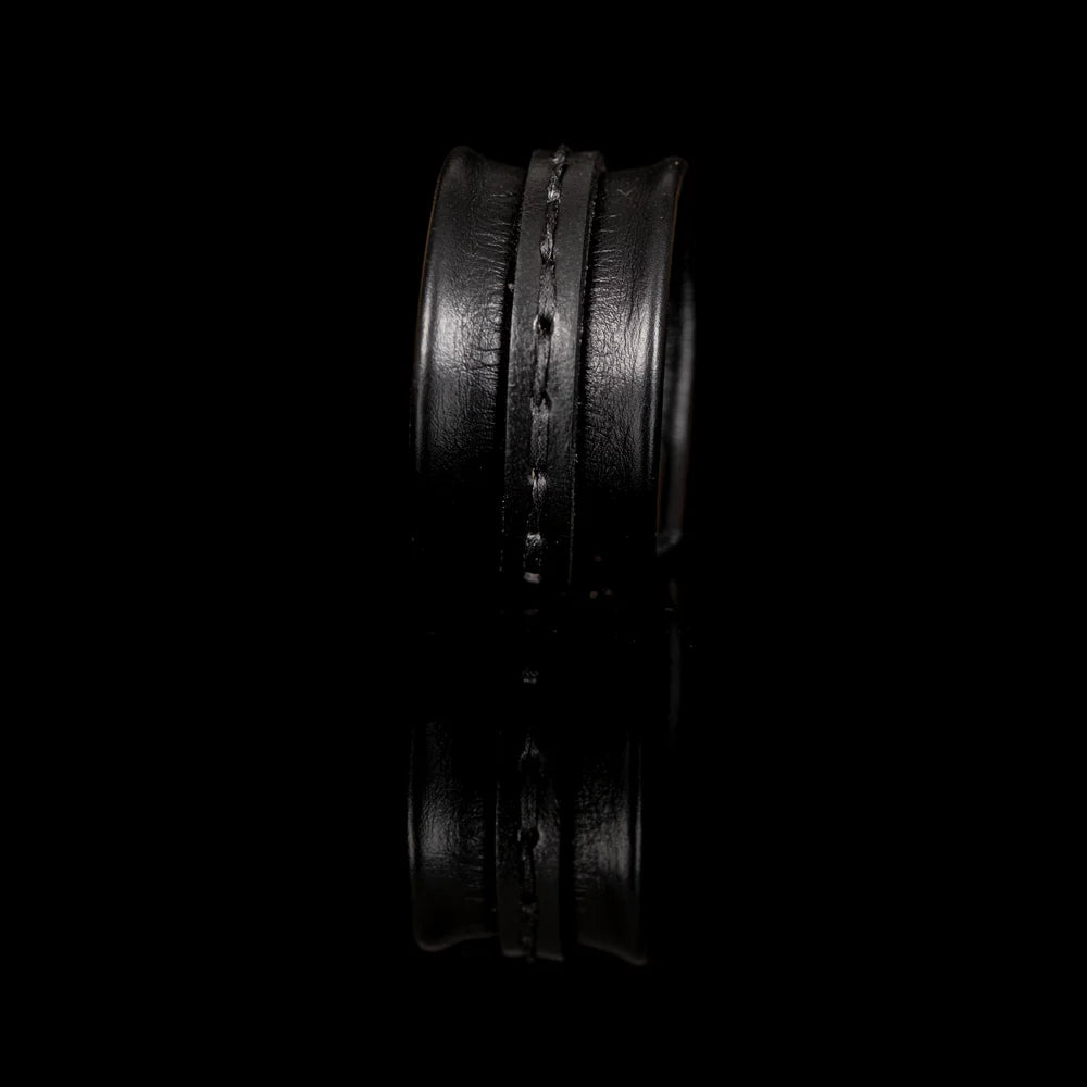 Black genuine leather cuff bracelet with a sculpted padded design, hand-stitched wrap strap detail, and handcrafted artisan finish on a white background.