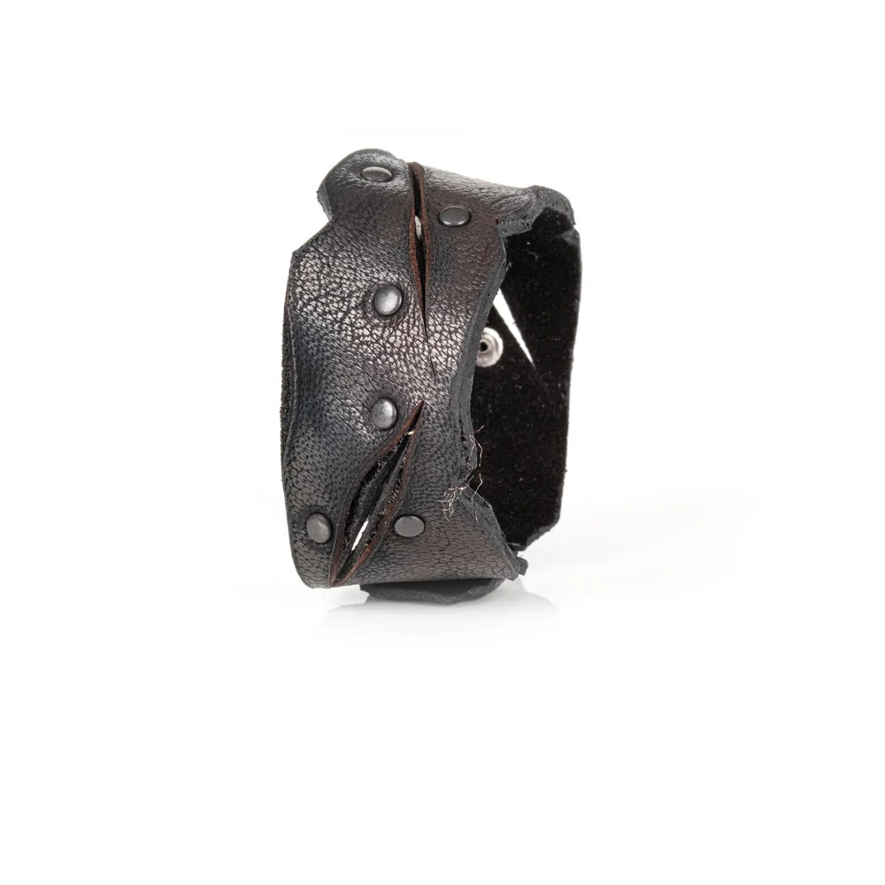 Black genuine leather cuff bracelet with sculpted cutout detailing, black rivet accents, and a handcrafted rugged artisan design, displayed on a white background.