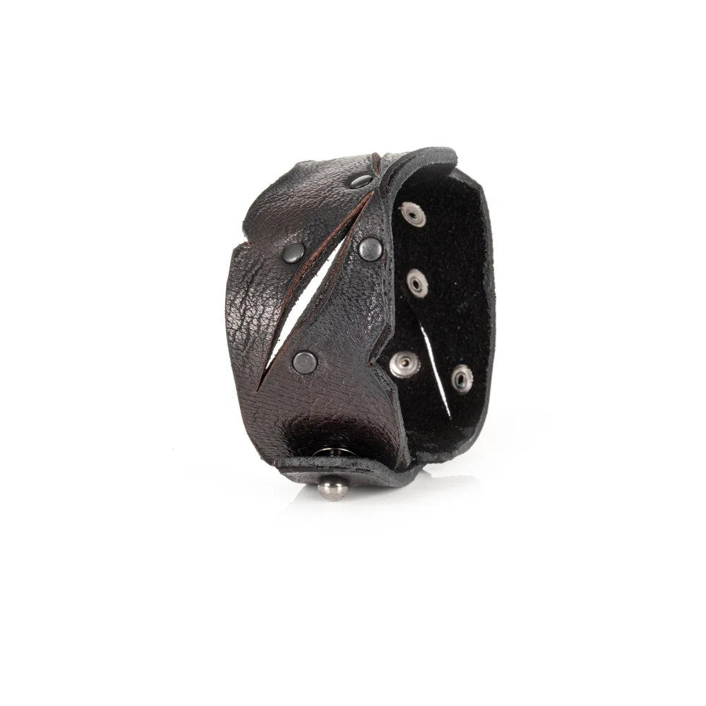 Black genuine leather cuff bracelet with sculpted cutout detailing, black rivet accents, and a handcrafted rugged artisan design, displayed on a white background.