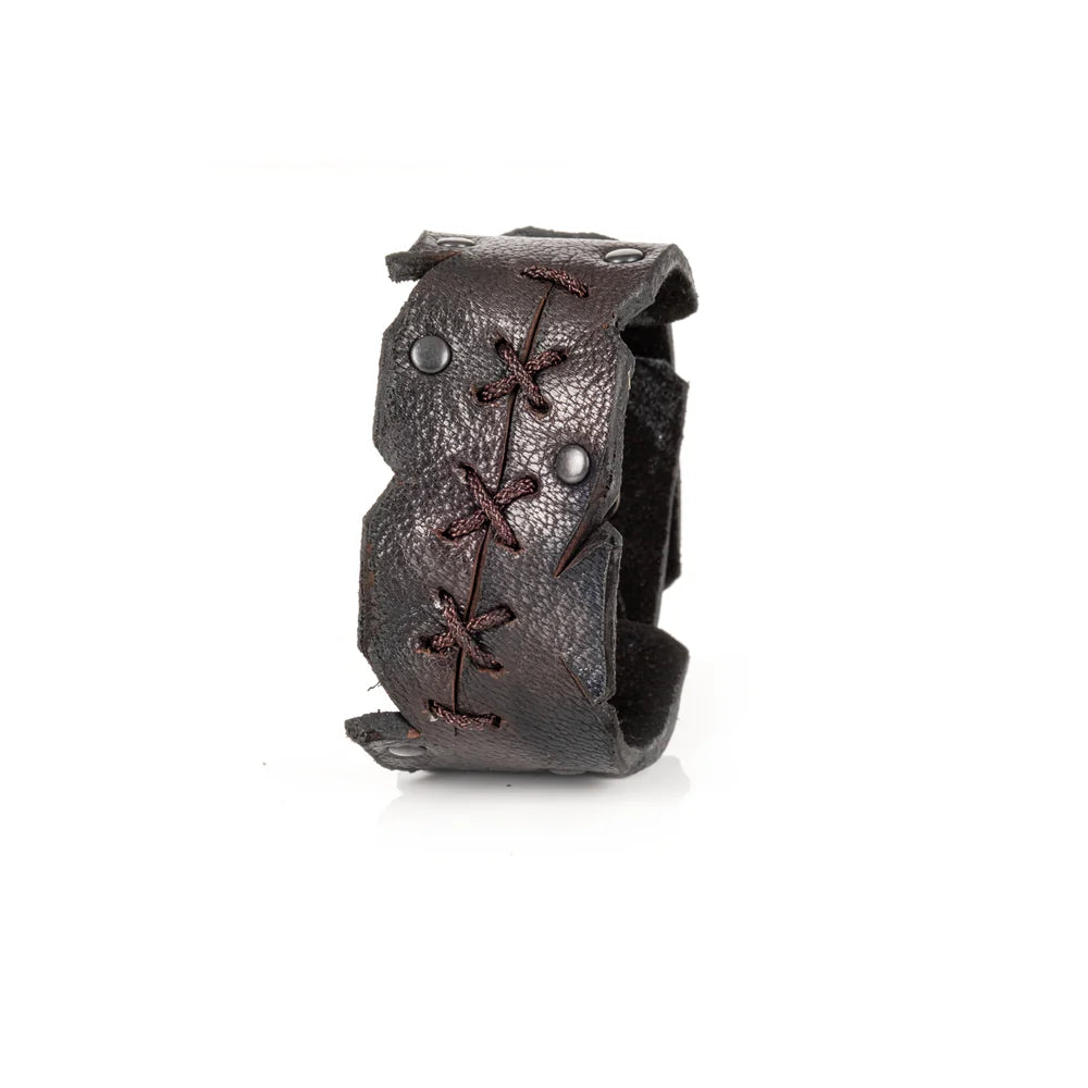 Black genuine leather cuff bracelet with hand-laced stitching, raw cut edges, and black rivet accents, handcrafted artisan statement accessory on a white background.