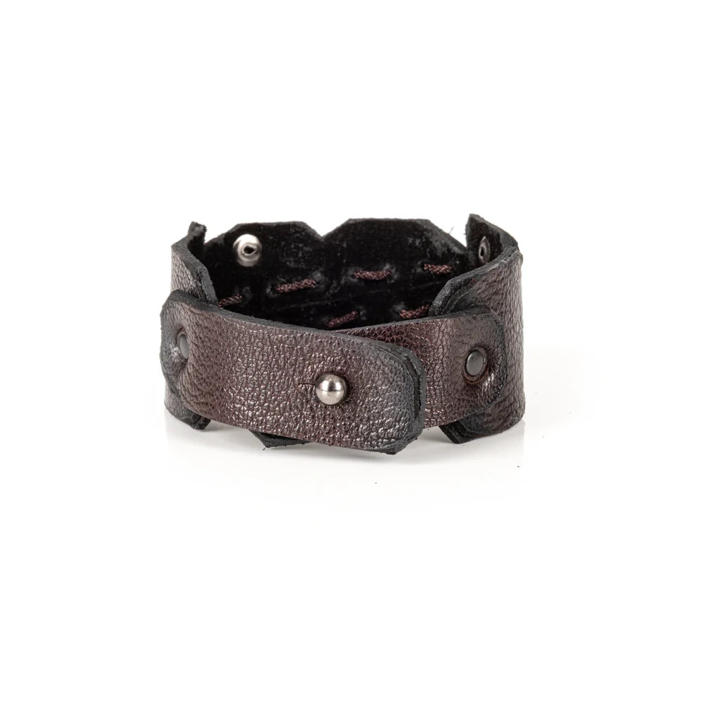 Black genuine leather cuff bracelet with hand-laced stitching, raw cut edges, and black rivet accents, handcrafted artisan statement accessory on a white background.