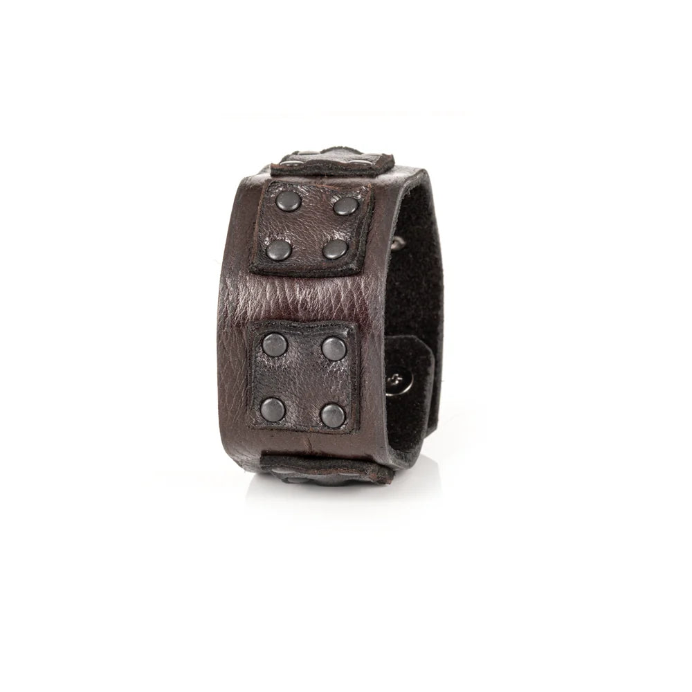 Black genuine leather cuff bracelet with layered square leather panels and black rivet detailing, handcrafted statement accessory with an industrial-inspired design, displayed on a white background.