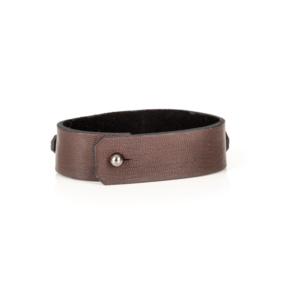 Men's handcrafted genuine leather cuff bracelet in dark brown featuring a wide minimalist design with a slim leather strip accented by matte black metal studs. Premium artisan men's leather wristband photographed on a clean white background.