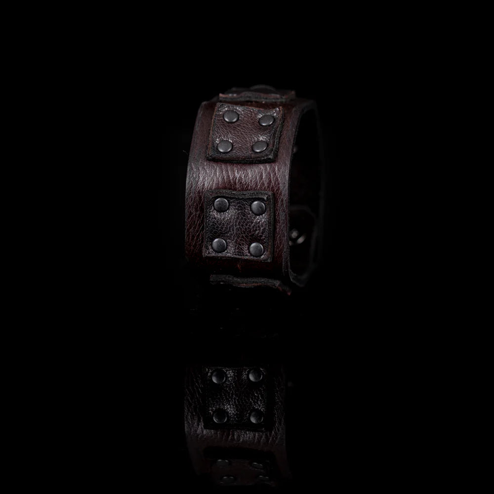 Black genuine leather cuff bracelet with layered square leather panels and black rivet detailing, handcrafted statement accessory with an industrial-inspired design, displayed on a white background.