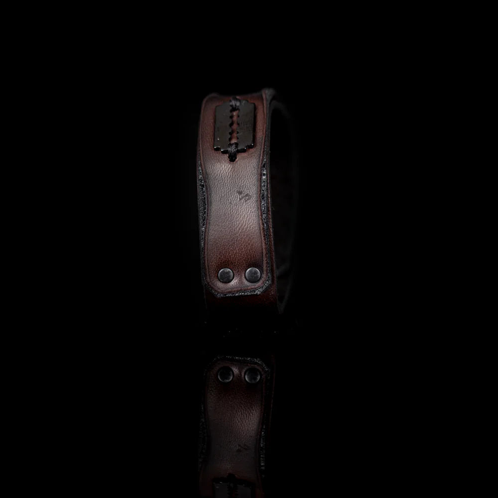 Men's handcrafted genuine leather cuff bracelet in dark brown featuring a wide minimalist design with black rivet hardware, hand-stitched razor blade accent, and premium artisan craftsmanship. Luxury men's leather wristband photographed on a clean white background.