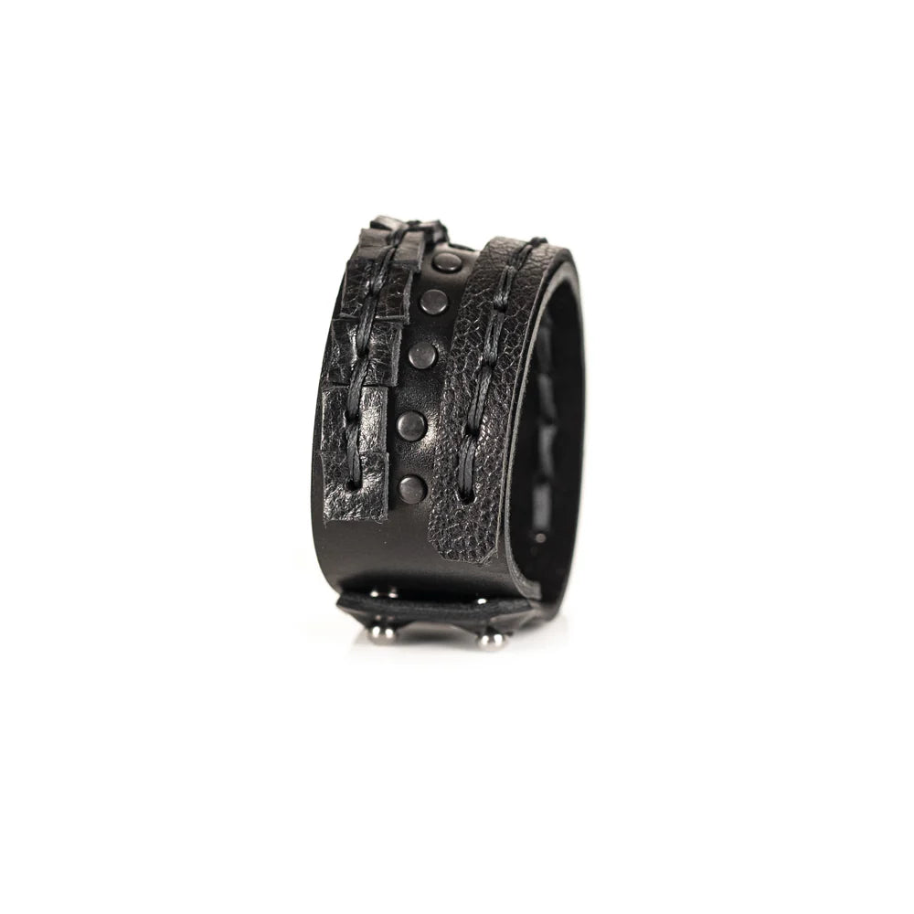Black genuine leather bracelet featuring layered hand-stitched straps, black studded detailing, and geometric cut leather accents, handcrafted statement accessory on a white background.