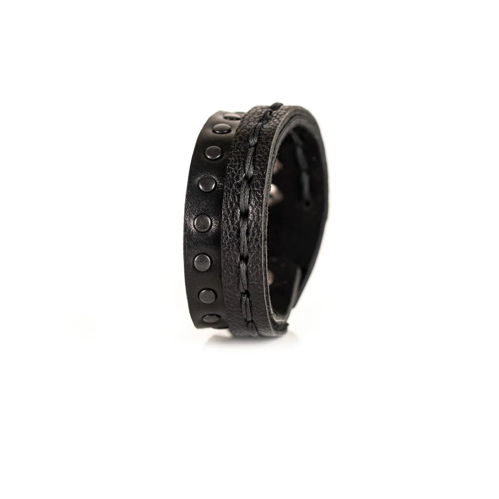 Black genuine leather bracelet featuring a hand-stitched leather band layered with a black studded strap, handcrafted statement accessory on a white background.