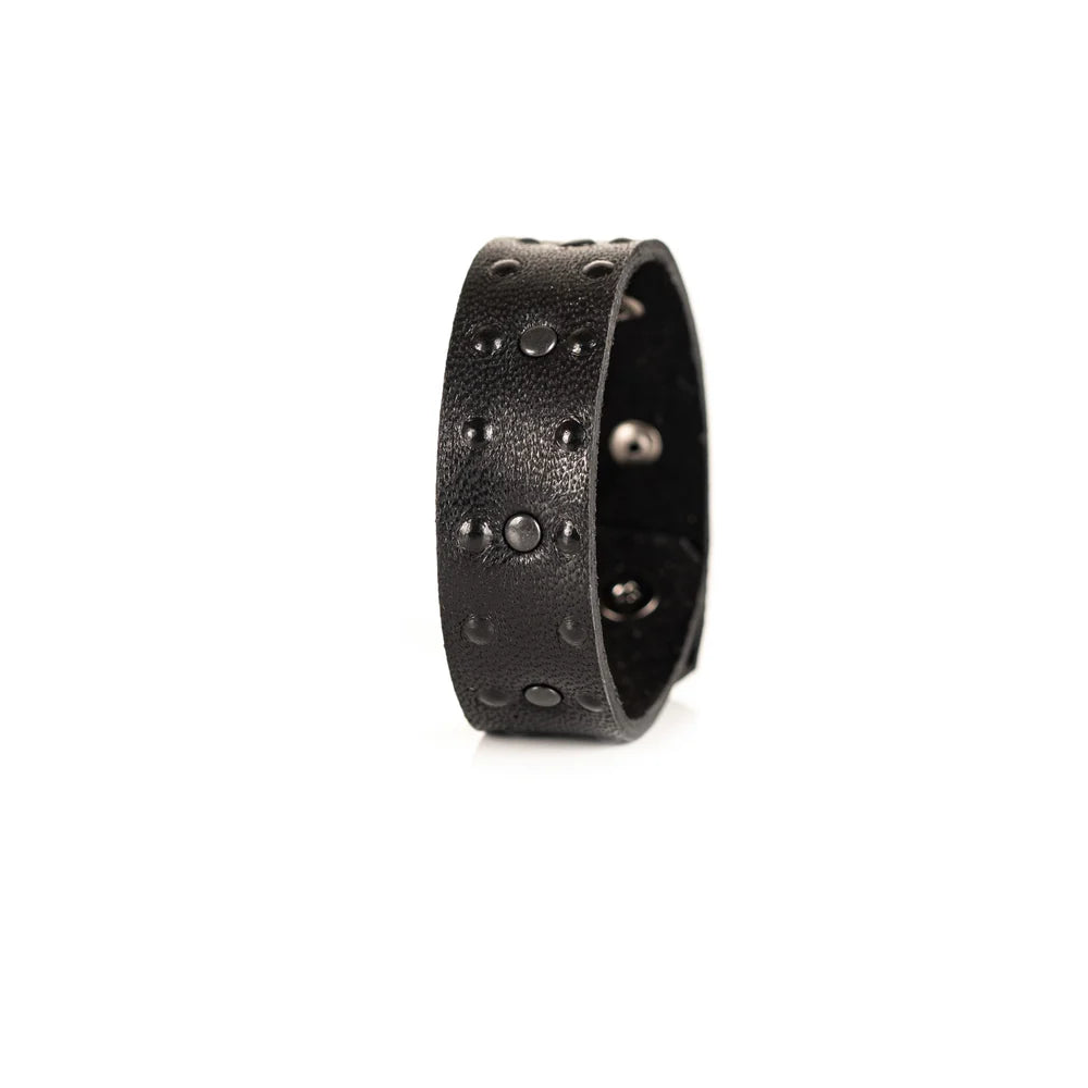 Black genuine leather cuff bracelet with black stud accents and textured leather finish, handcrafted minimalist statement accessory on a white background.