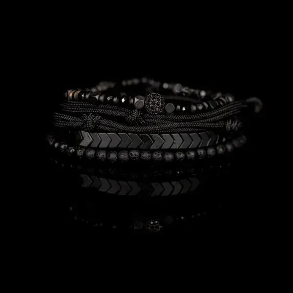 Black layered men’s bracelet with lava stone beads, hematite accents, braided cord, and adjustable closure on a white background.