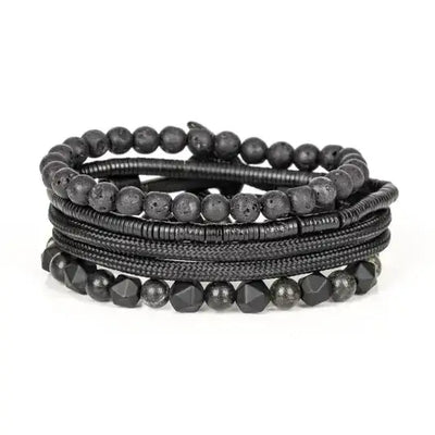 Layered men’s bracelet set featuring black lava stone beads, faceted black stone beads, braided black cord wraps, and metallic hematite accents in a monochromatic stacked design, displayed on a white background.