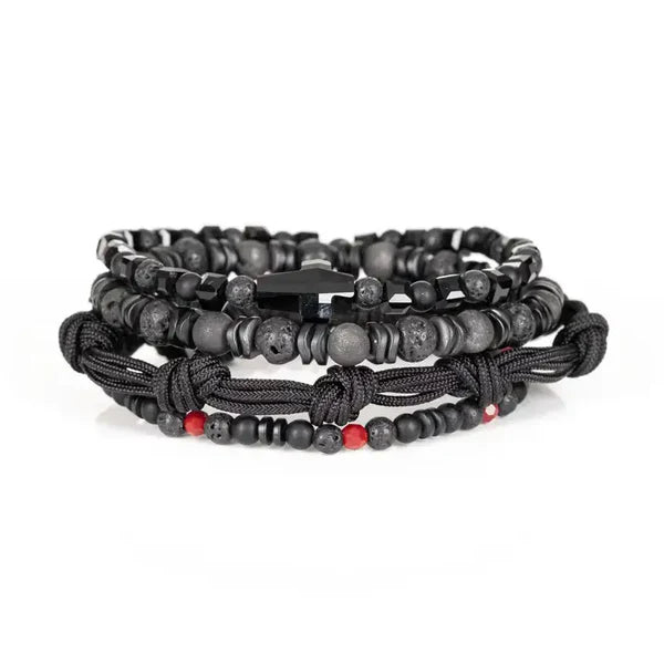 Layered men’s bracelet set featuring black lava stone beads, faceted black crystal beads, matte gray stone beads, braided black cord wraps, red accent beads, and a black arrow-shaped centerpiece, displayed on a white background.