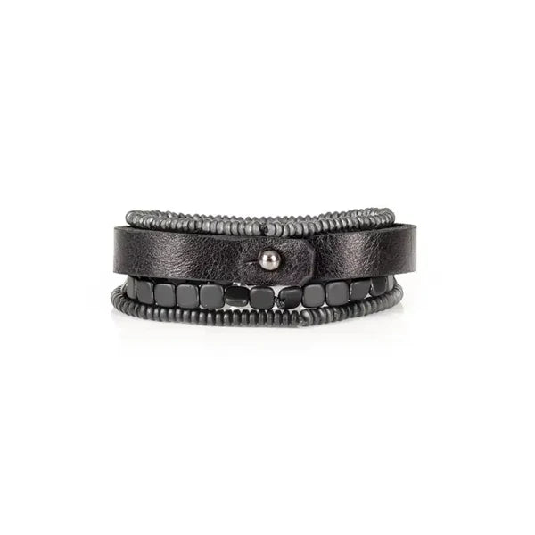 Layered men’s bracelet set featuring a black leather band with a black metal plate, matte hematite cube beads, and hematite disc beads in a sleek monochromatic design, displayed on a white background.
