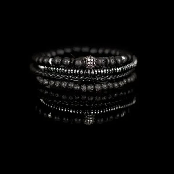 Black layered men’s bracelet with lava stone beads, braided leather detail, silver-tone accents, and crystal pavé centerpiece on a white background.