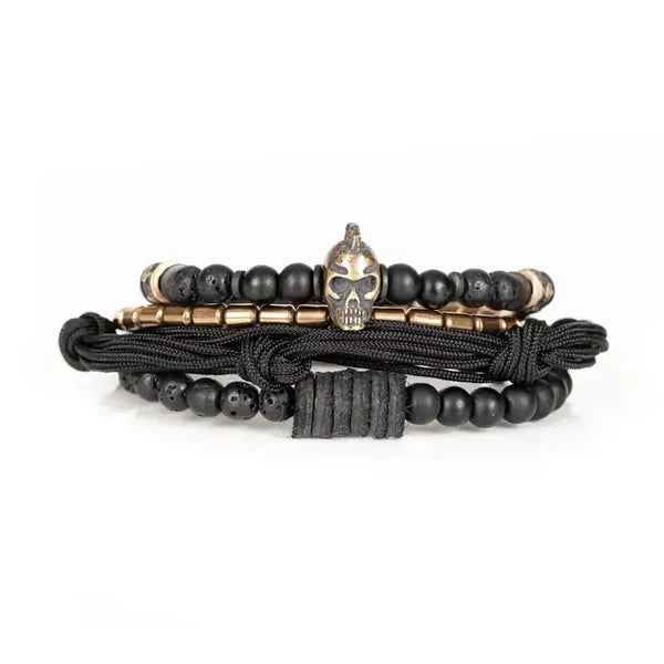 Black layered men’s bracelet with matte black beads, lava stone accents, braided cord wraps, bronze-tone metal beads, and a Spartan skull centerpiece on a white background.